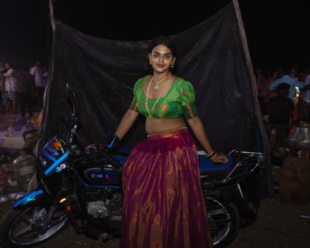 Kareena leaning against a motorcycle at Koovagam festival at night