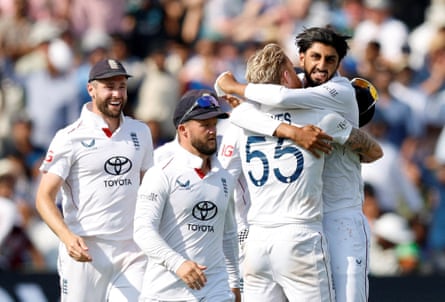 England’s Shoaib Bashir facing the camera celebrates in a hug around the shoulders with Ben Stokes who is facing away. Two other players are visible