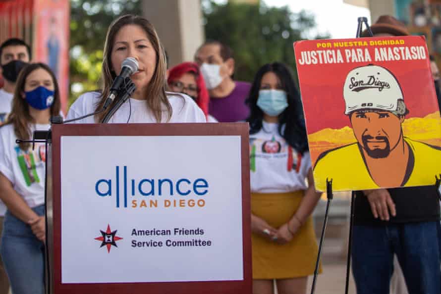 woman speaks at podium next to poster that says ‘Justicia para anastasio’