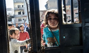 A girl looks at a dead body among the rubble of damaged buildings in Cizre.