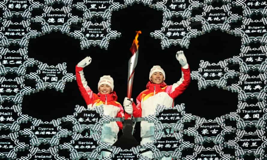 Dinigeer Yilamujiang and Zhao Jiawen light the snowflake-shaped Olympic cauldron at the opening ceremony.