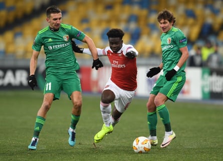 Bukayo Saka dribbles the ball between Vyacheslav Sharpar and Pavlo Rebenok