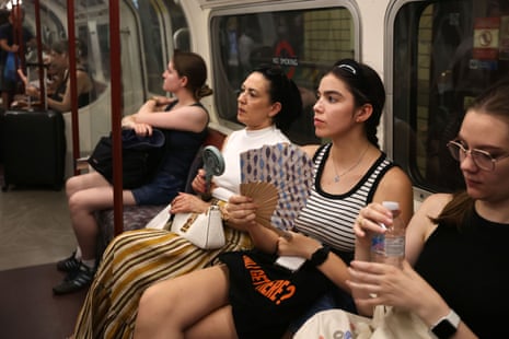 Commuters use electric and hand fans while riding the London Underground during hot weather in London on 26 June