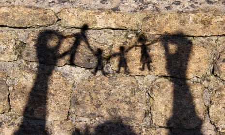 A paper chain of a family shown in silhouette against a wall