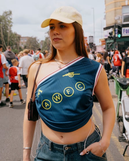 A young woman wearing an asymmetrical blue vest with an Arsenal logo