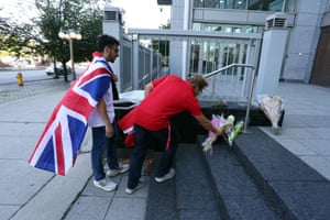 People place flowers on the front steps of the British High Commission in Ottawa, Canada
