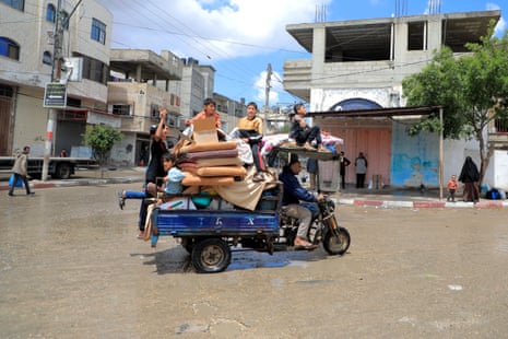 People leave Rafah with their belongings on a trailer attached to the back of a motorbike