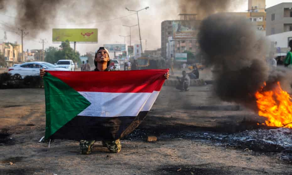  A protester holds the Sudanese flag next to burning tires during a demonstration against the coup in the capital Khartoum on Tuesday.