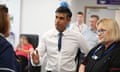 Rishi Sunak, soaked by rain, walks back in to 10 Downing Street after issuing a statement at a lectern to call a general election. He is seen from behind, dripping wet in a dark blue suit, stepping over the threshold.