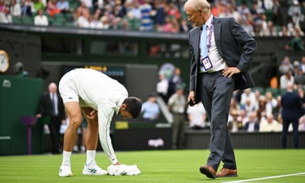 Novak Djokovic jokingly helps to dry the wet grass on Centre Court