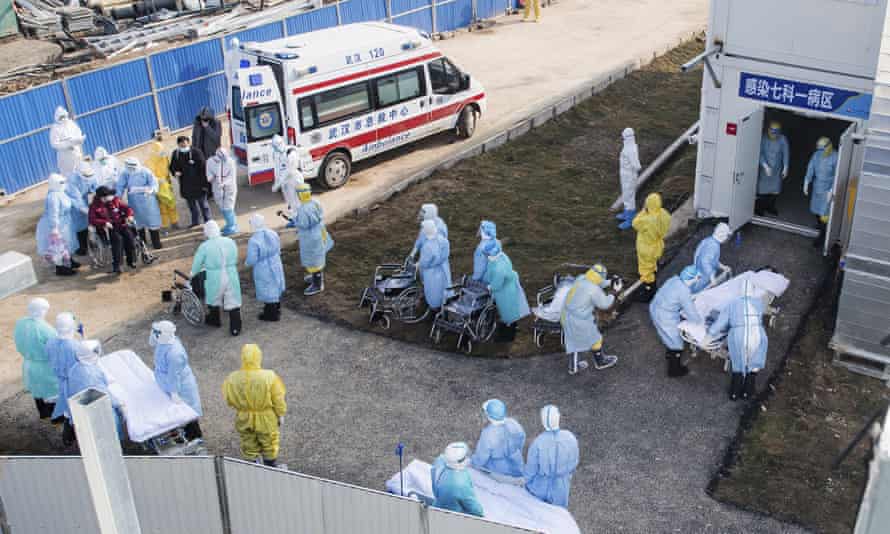 Medical workers in protective suits help transfer the first group of patients into the newly-completed Huoshenshan temporary field hospital