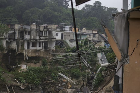 A shot across a river shoes collapsed houses on the far bank. A TV aerial hangs upside down in the foreground