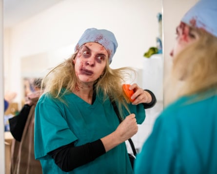 A perfomer in bloody scrubs with red irises brushes her hair.