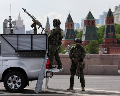 Russian security personnel stand guard next to a pickup truck equipped with a machine gun near the Kremlin in central Moscow, Russia.