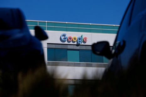 Google logo between two parked cars on white building with blue windows