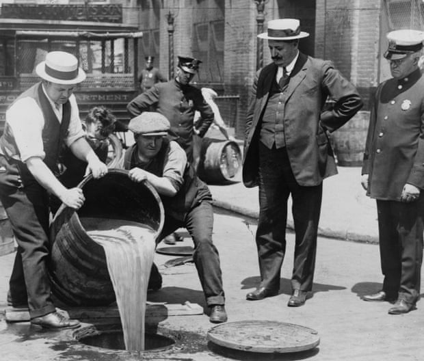 A barrel of confiscated illegal beer being poured down a drain.