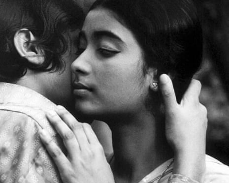 A teenager with closed eyes embraces someone, her hands gently placed on their shoulder and raised near their face