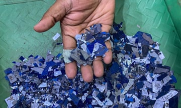 A hand holding shredded pieces of a thin blue material
