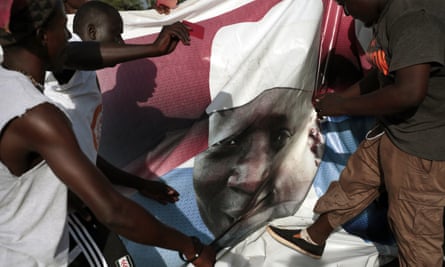 Gambians tear down a poster of Yahya Jammeh after he was defeated in the country’s election.