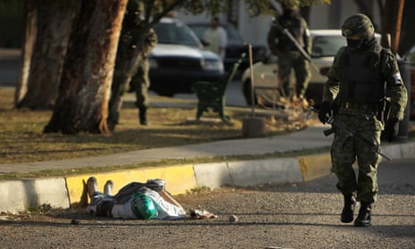 A member of the military police walks by a body with a mask in the street, one of numerous murders over a 24-hour period, on 26 March 2010 in Ciudad Juárez, Mexico, which has been racked by violent drug-related crime.