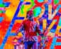 Enter Shikari singer performs on stage, arms outstretched, against a colourful graffiti backdrop