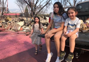 The Guterrez children wait as their father, Artemio Guterrez, salvages a few items from their scorched mobile home in Talent, Oregon