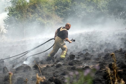 Seorang petugas pemadam kebakaran bekerja selama kebakaran hutan Inggris pada musim panas 2022.