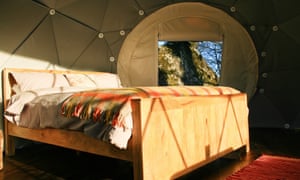 Gaze across meadows from your bed. A shot of the bed in the glamping dome.