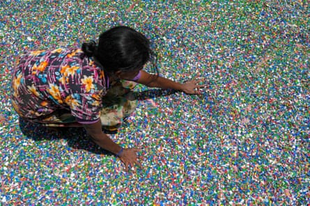 A worker arranges processed plastic chips made of recycled plastic bottles at a recycling facility in Panagoda, Sri Lanka.
