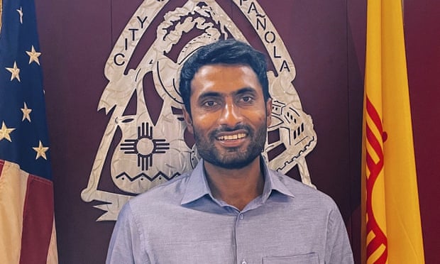 A portrait of a Muslim man in front of flags.