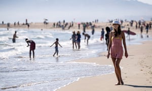 A woman wearing a face mask walks at Venice Beach during a heatwave amid the coronavirus pandemic, in Los Angeles, California, USA, 11 July 2020