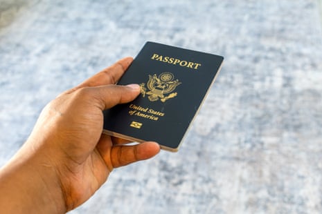 A hand holds up a dark blue United States passport at an angle