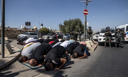 People perform Friday prayers on the street as Israeli police prevent them from entering the Old City and the al-Aqsa mosque complex in East Jerusalem.