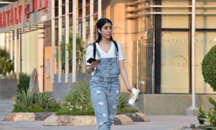 Manahel al-Otaibi wears dungarees walking down the street.