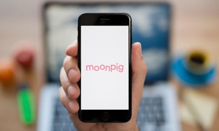Someone holding up a phone with the pink Moonpig logo visible on the screen