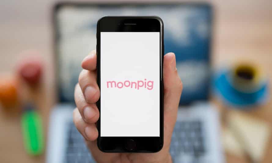 شخصی تلفن را در دست دارد که روی آن آرم صورتی Moonpig دیده می شود