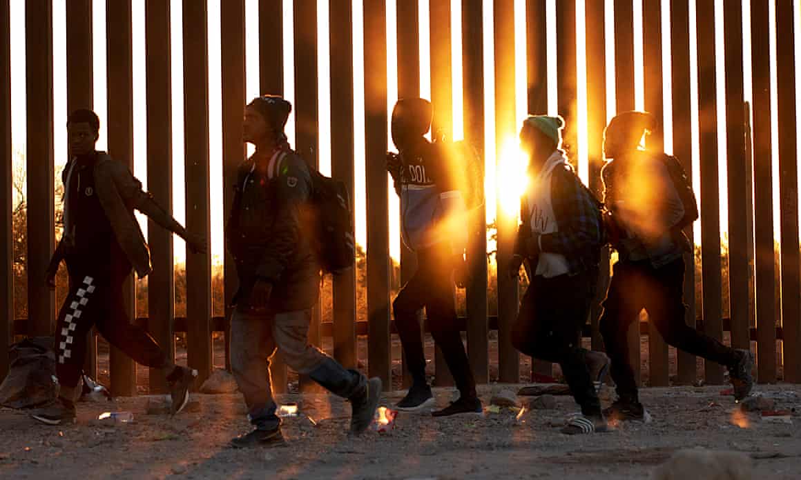 Immigrants walk along the US border wall looking for Border Patrol agents in Lukeville, Arizona