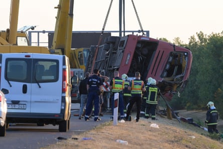 Emergency workers look on as a crane lifts the bus from the side of the motorway