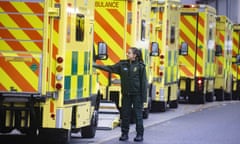 An NHS worker stands next to a row of ambulances in Whitechapel, east London