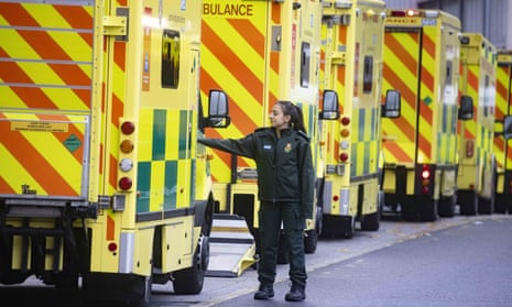 An NHS worker stands next to a row of ambulances in Whitechapel, east London
