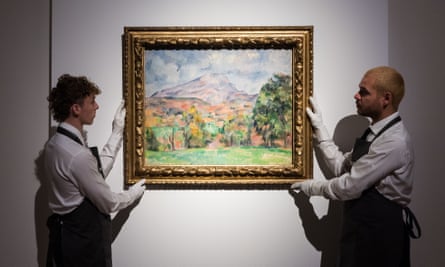 Art handlers hold up La Montagne Sainte-Victoire, by Paul Cézanne.