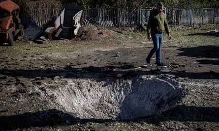 Polyanytsia volunteer Roman Kasyan, 42, looks at the funnel left by a rocket that hit a car park and power lines in Bombay