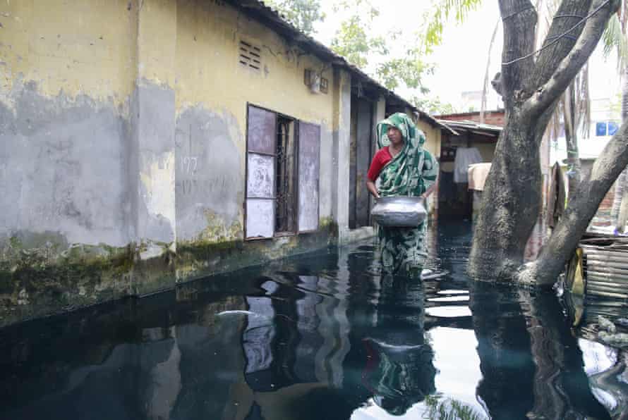 A Bangladeshi woman walks through the polluted and quickly stagnating water as she looks for drinking water at Demra in Dhaka