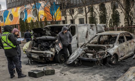 People inspect damaged vehicles after the strike.