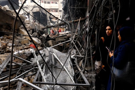 Two women looking at a tangle of wreckage and rubble of a collapsed building