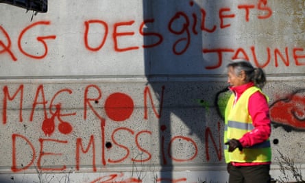 A protester outside a shopping centre in Nantes, walks past a wall with graffiti saying: 'Macron, resign.’