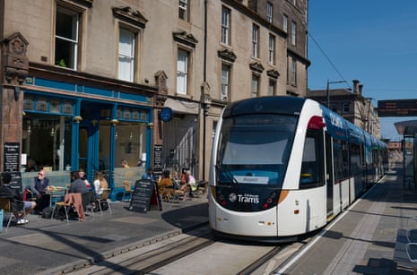 A tram passes a pavement cafe in Leith