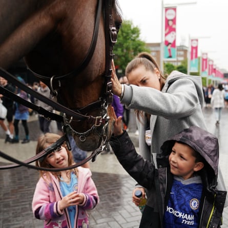A Chelsea fan pets a police horse along Wembley Way in the rain