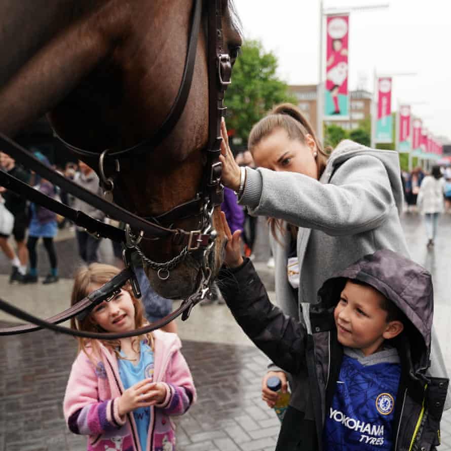 A Chelsea fan pets a police horse along the Wembley Way in the rain