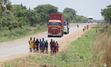 A group of African children and a man run along a road